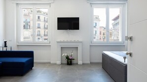 A modern living room with a fireplace, a flat-screen TV, and a sofa. - Suite nel Largo (Cagliari)