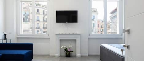 Uma sala de estar moderna com lareira, televisão de tela plana e um sofá.