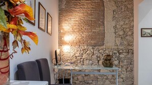 A room with a stone wall, a glass table, and a chair. - Suite nel Largo (Cagliari)