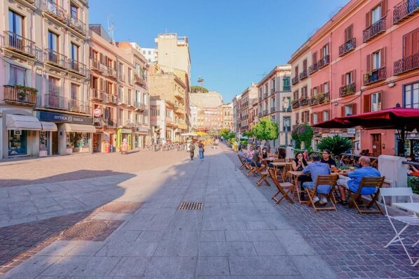 Une rue piétonne bordée de boutiques et dotée d’espaces de terrasses extérieures de part et d’autre.