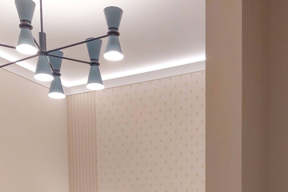 A bedroom with a bed, bedside table, lamp, and ceiling light fixture.