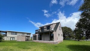 Uma casa moderna de dois andares com varanda, telhado plano e uma pequena garagem anexa.