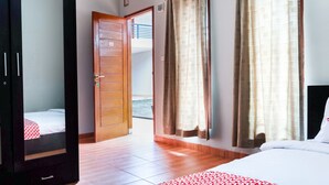 Une chambre d’hôtel avec un lit, une armoire, une porte donnant sur un balcon et des rideaux.