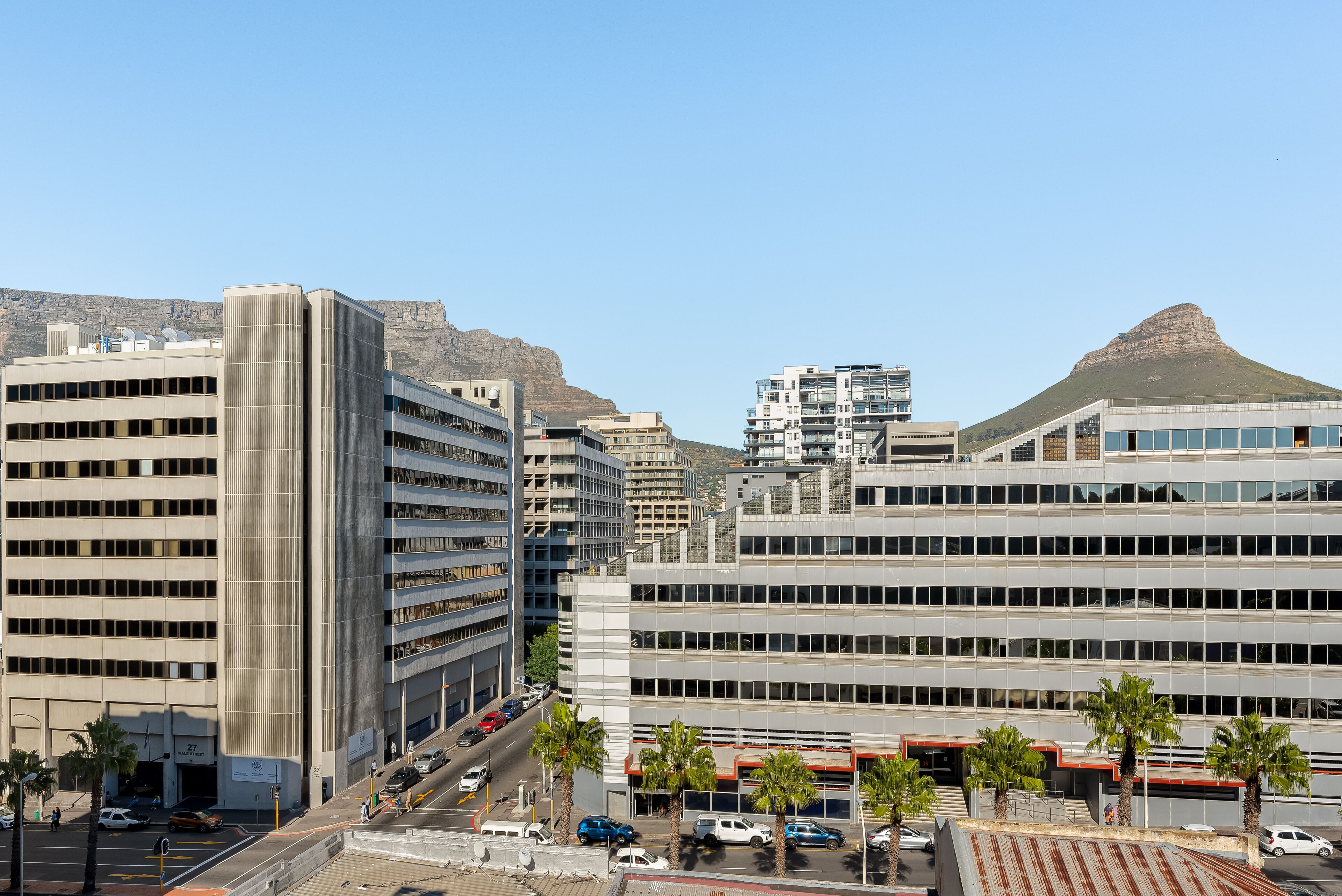 A multi-story building with a parking lot and a mountain in the background.