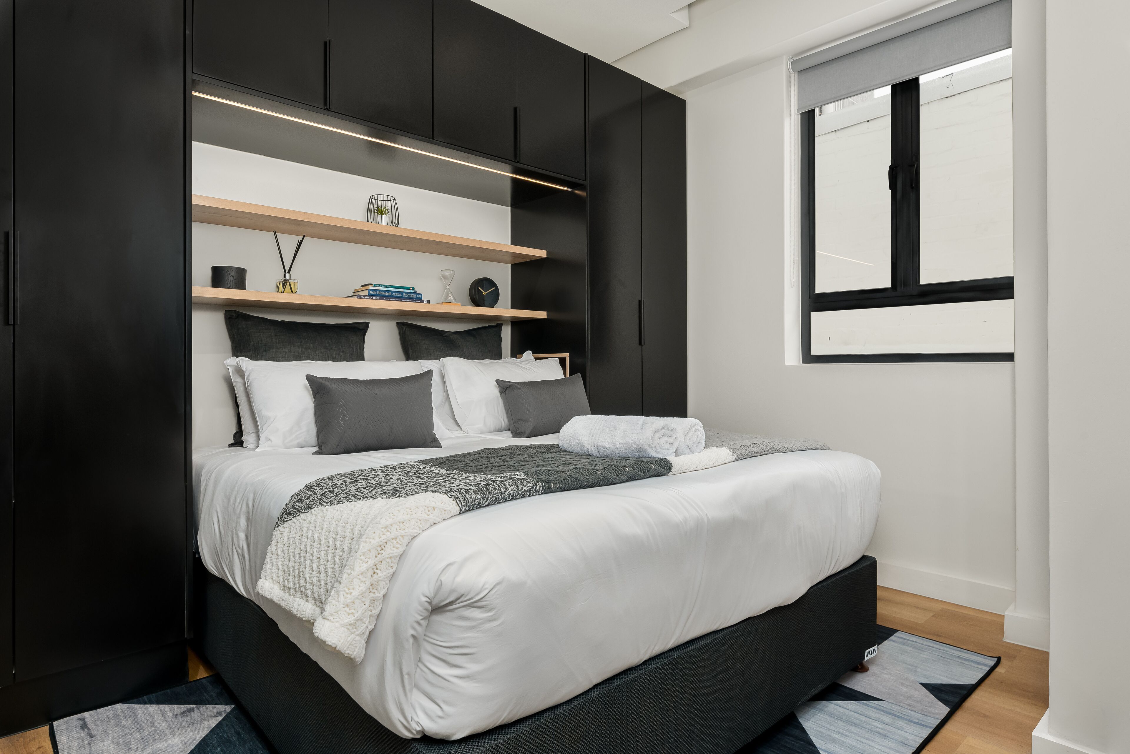 Ein modernes Schlafzimmer mit einem großen Bett, eingebauten Regalen und einem Fenster.