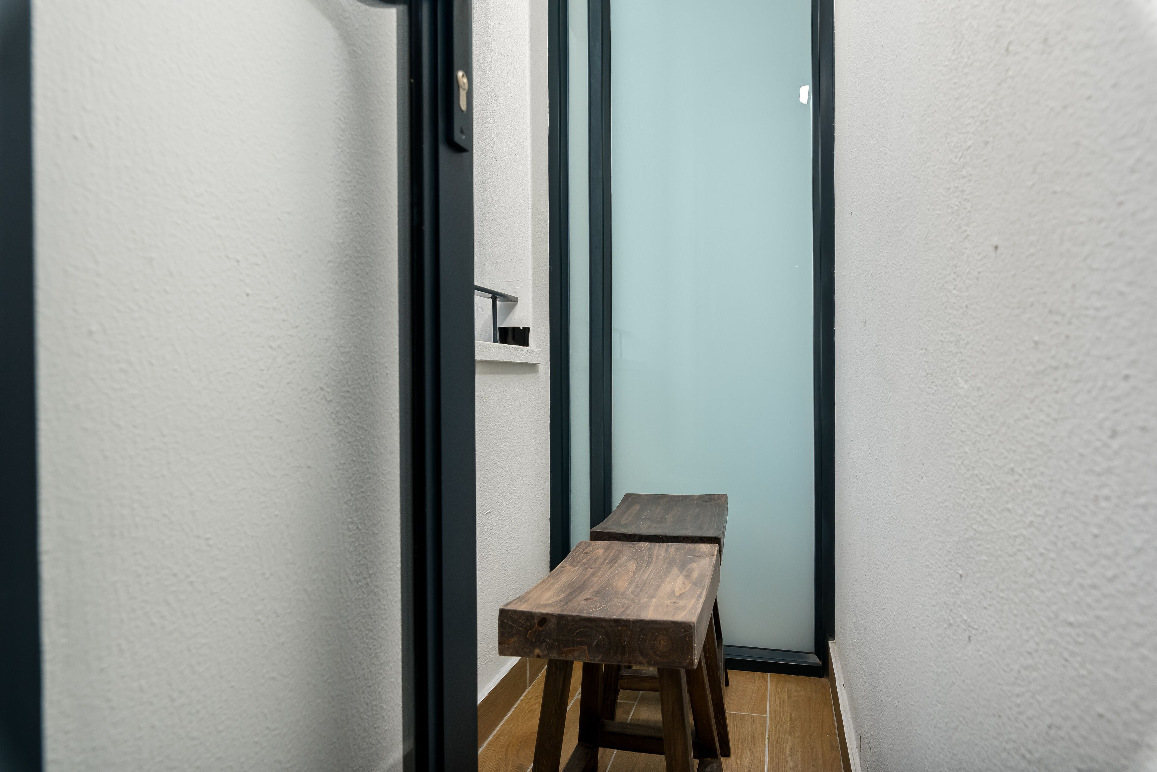 A narrow hallway with two wooden tables and a white door.