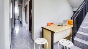 A corridor with a staircase, a desk with a laptop, and two stools. - Hotel O Teluk Betung Near Taman Dipangga Formerly Z Hotel (Bandar Lampung)