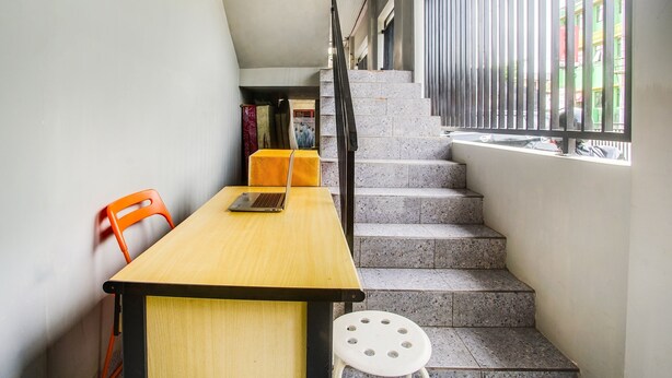 A narrow stairway with a wooden desk and a laptop, a white stool, and a red chair. - Hotel O Teluk Betung Near Taman Dipangga Formerly Z Hotel (Bandar Lampung)