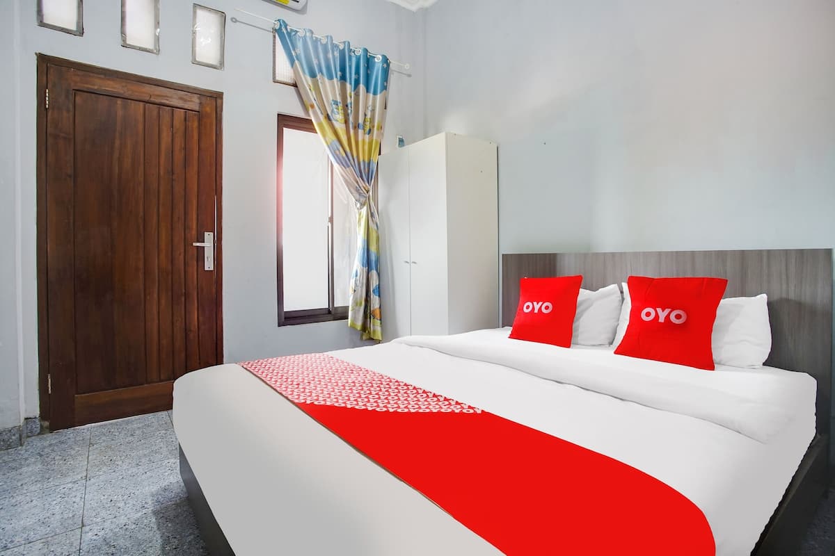 A hotel room with a large bed, a wardrobe, a door, and a window with curtains.