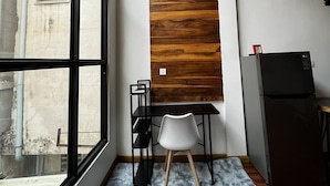 Eine moderne Küche mit großem Fenster, einer Wand in Holzoptik, einem schwarzen Kühlschrank und einem weißen Stuhl.