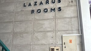 Eine Wand mit der Aufschrift "LAZARUS ROOMS", die ein Hotel oder ein Quartier kennzeichnet.