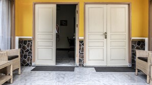 Entrada de hotel com duas portas, parede de pedra e chão de azulejos.