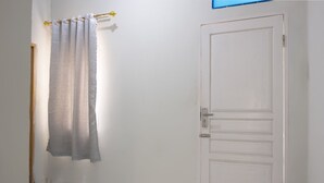 Um banheiro com porta branca, porta-toalhas com toalha e um tapete azul no chão.