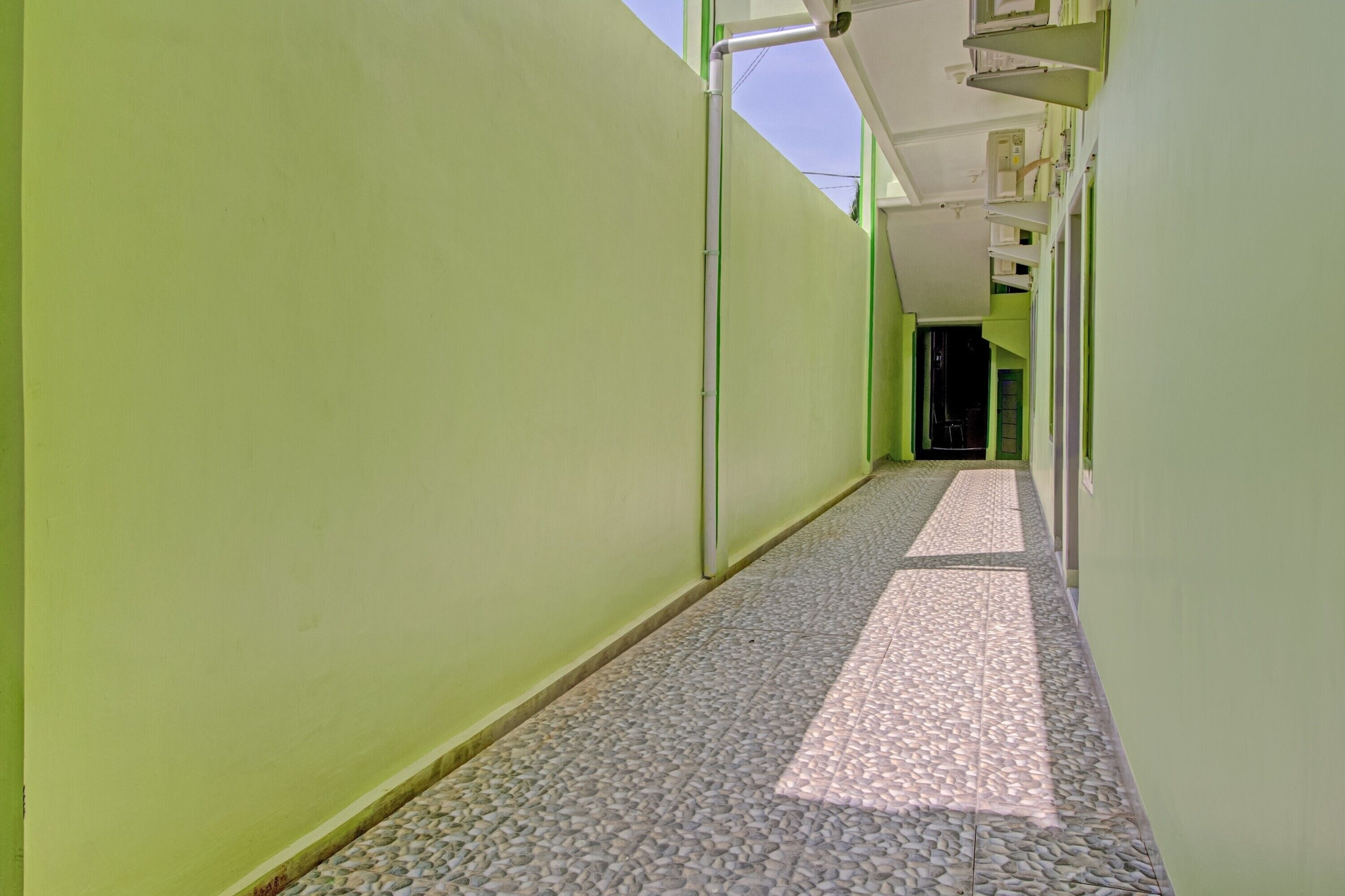 A narrow hallway with green walls and a pebble-patterned floor.