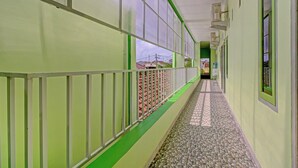 A corridor with a tiled floor, green walls, and windows.