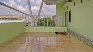 A spacious balcony with a tiled floor, a metal railing, and a view of buildings in the background.