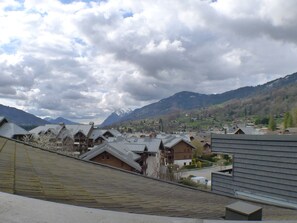 A town with traditional wooden houses, a river, and mountains in the background.