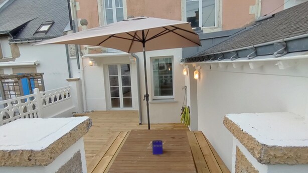 A house with a wooden deck, a white fence, and a large umbrella.
