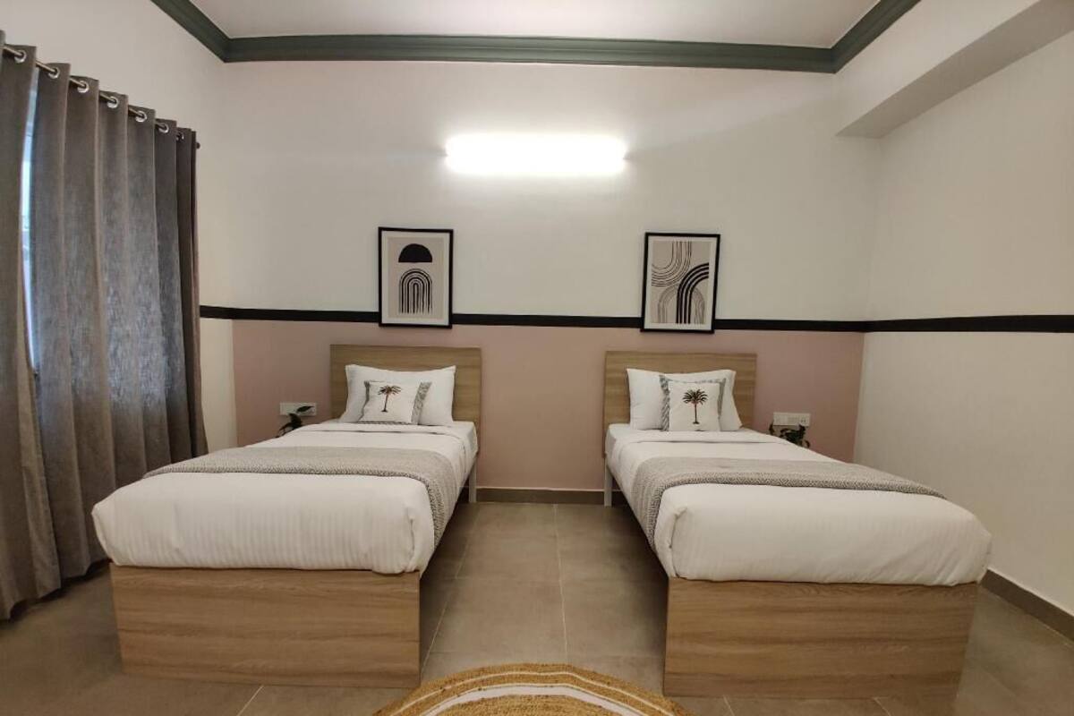 A hotel room with two beds, a large window with curtains, a flat-screen TV, and artwork on the wall.