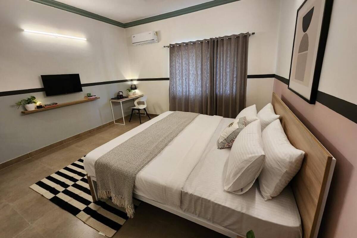 A bedroom with a bed, a TV, a desk, and a chair.