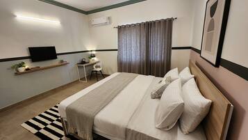 A neatly arranged bedroom with a bed, bedside table, chair, and a desk with a chair.