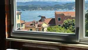 Une fenêtre donnant sur une ville côtière, des bâtiments et un pont situé au loin.