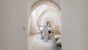 Een eetgedeelte met een stenen boog, een witte tafel en stoelen, en een open haard.