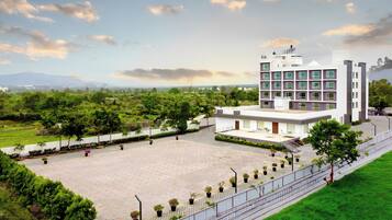 A modern building with a spacious courtyard, surrounded by greenery and a clear sky.