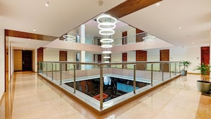 A spacious lobby with a central atrium, glass railings, and a modern chandelier. - Effotel by Sayaji Sarola (Bhor)