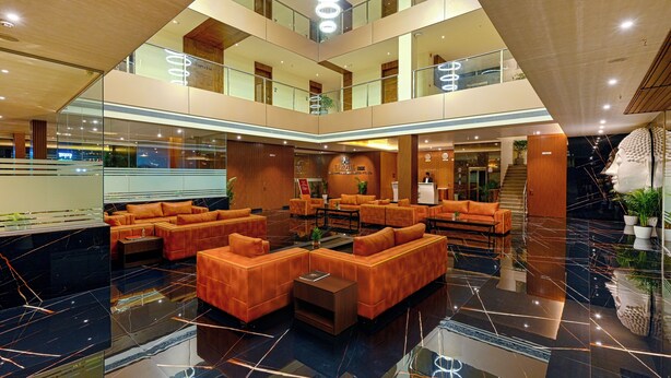 A spacious lobby with a central seating area, a reception desk, and a staircase leading to upper floors. - Effotel by Sayaji Sarola (Bhor)