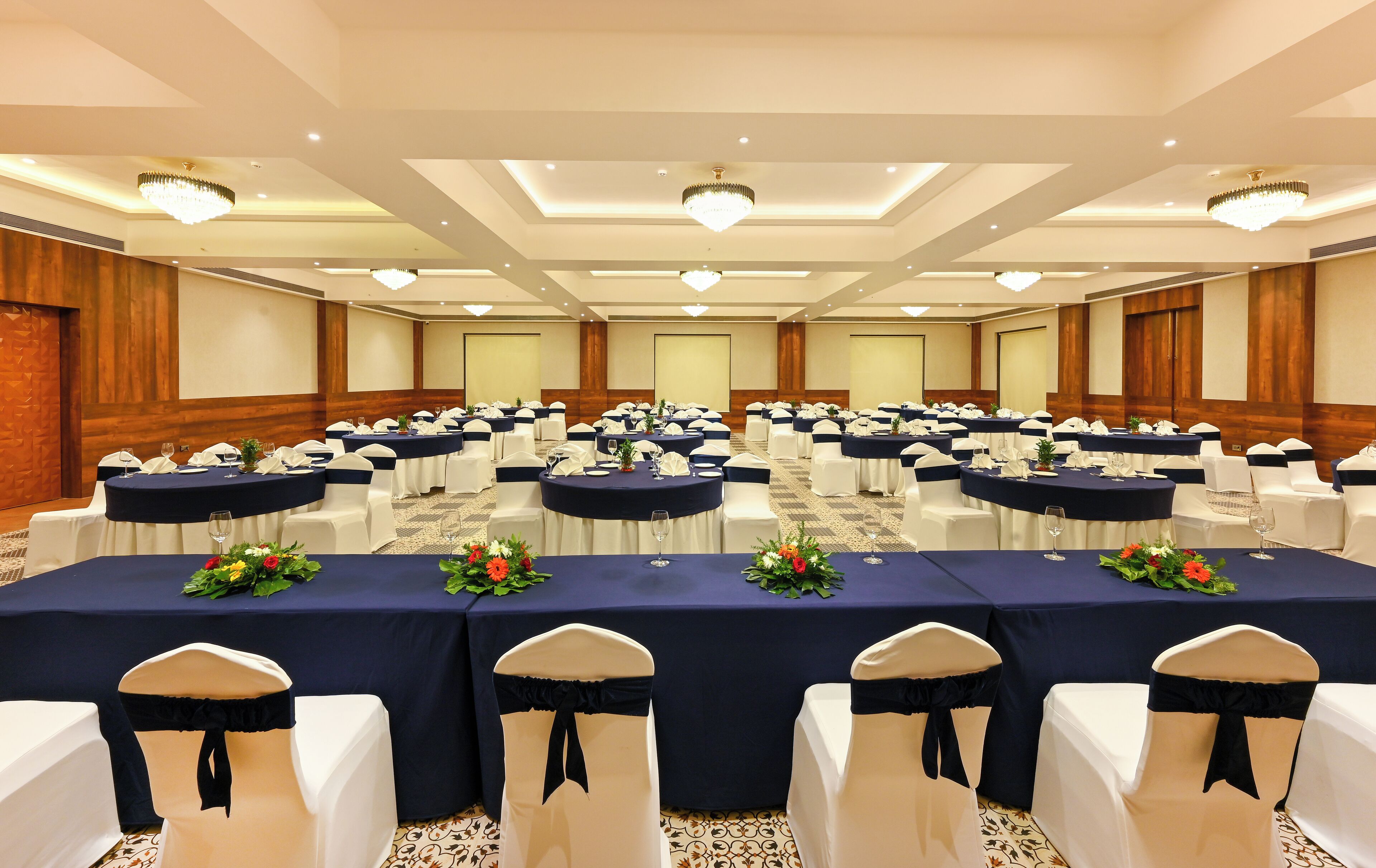 A conference room with round tables, white chairs, and blue tablecloths.