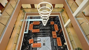 A multi-level atrium with a central chandelier, glass railings, and orange seating areas. - Effotel by Sayaji Sarola (Bhor)
