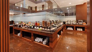 A modern hotel lobby with a central buffet area featuring various food items and a glass-enclosed upper level. - Effotel by Sayaji Sarola (Bhor)