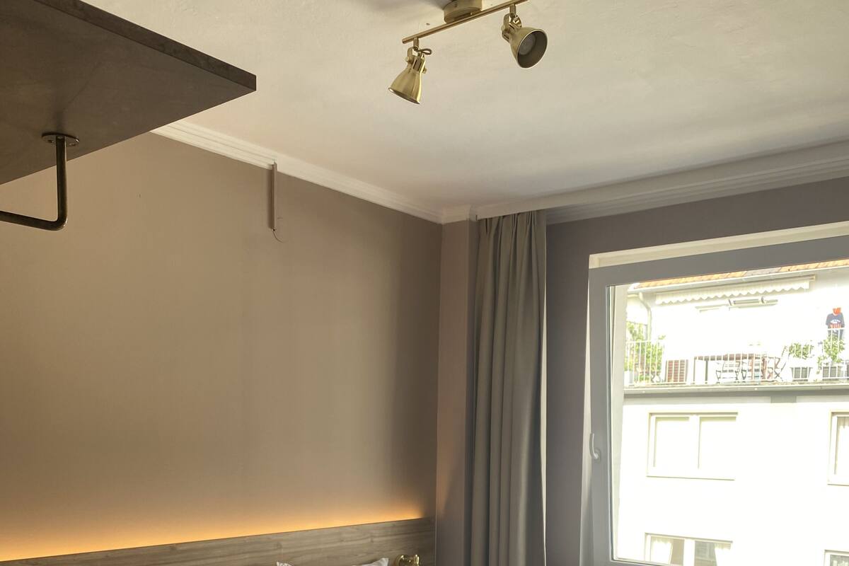 Hotelkamer met een groot bed, hoofdeinde met een lamp, raam met gordijnen en uitzicht op buiten.