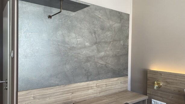 Een moderne badkamer met een grijze marmeren wand, een houten wastafelmeubel en een inbouwkast.