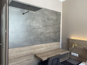 Un baño moderno con pared de mármol gris, tocador de madera y estante empotrado.