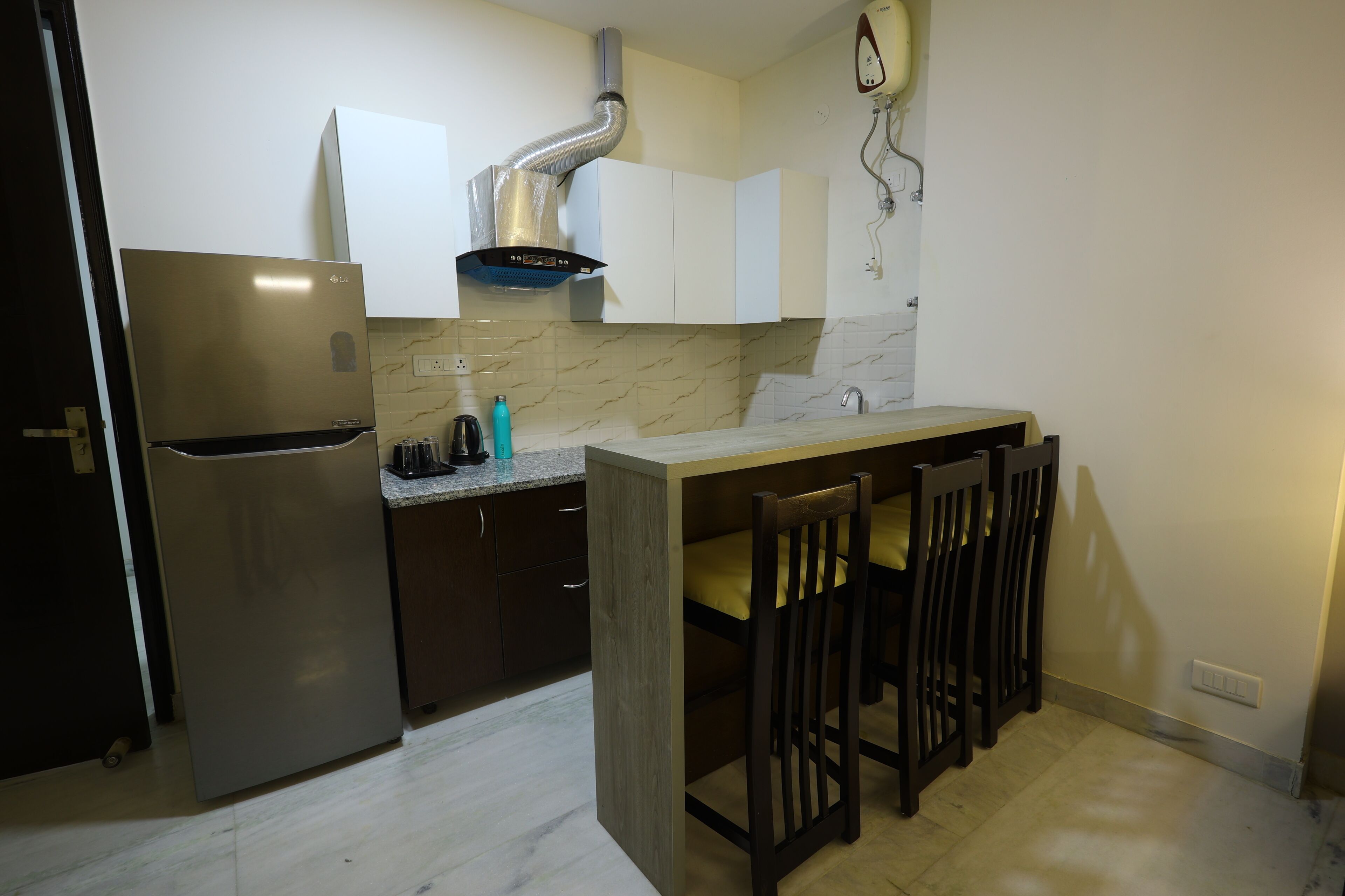 A compact kitchen with a stainless steel refrigerator, a built-in stove, and a wooden island with bar stools.