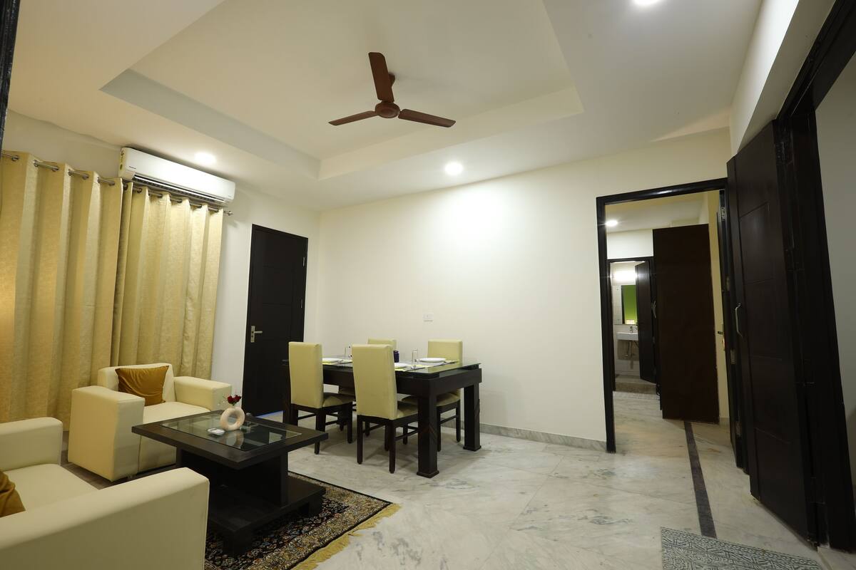 A modern living room with a dining area, a ceiling fan, and a view into another room.
