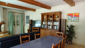 A dining area with a table and chairs, a wooden cabinet with books, a television, and a potted plant. - Villa "La Verdoulento" au Calme et à L'abri des Regards Avec Piscine 6mx12m (AVIGNON)