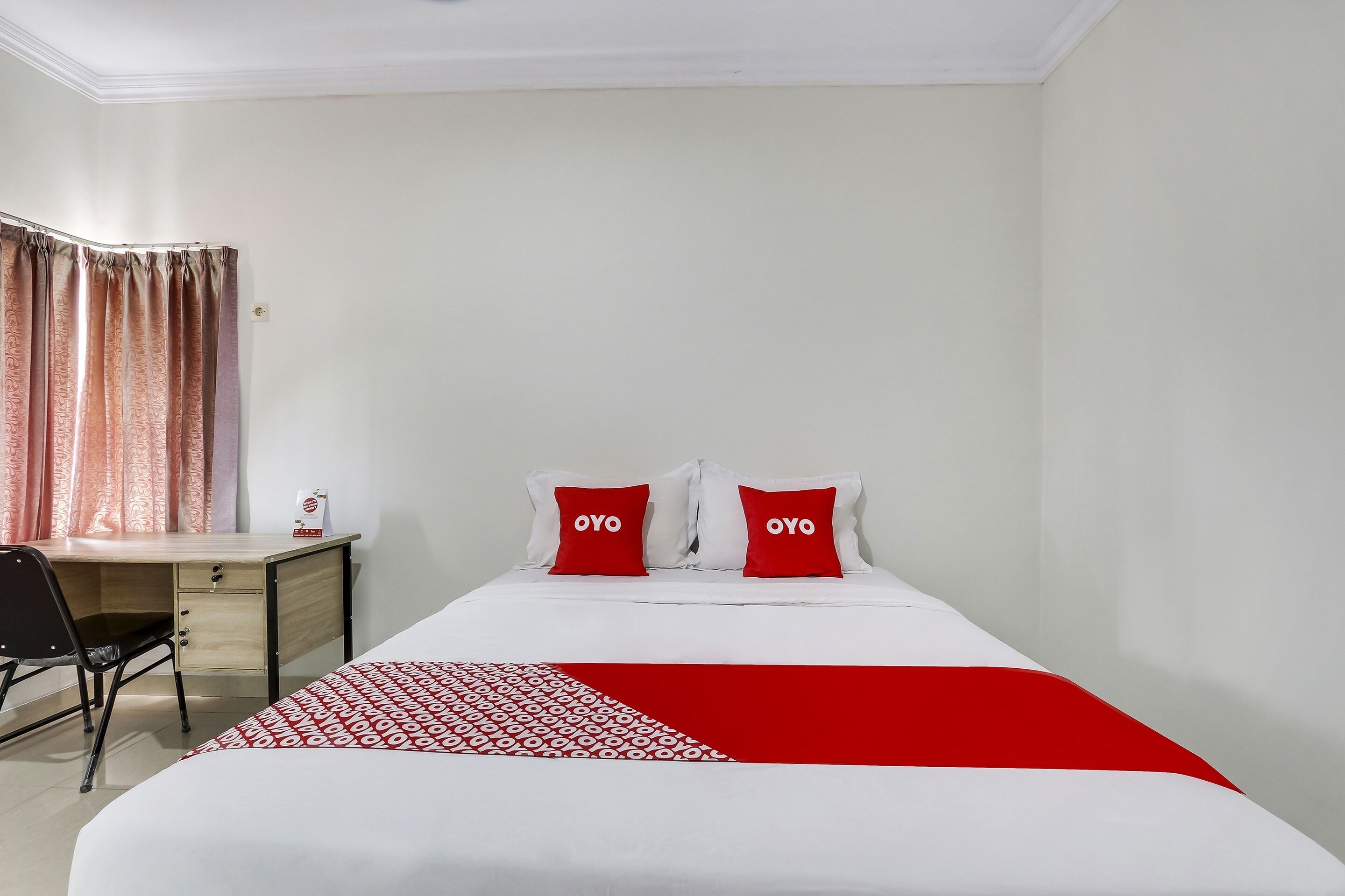 A hotel room with a bed, a desk, and a chair.