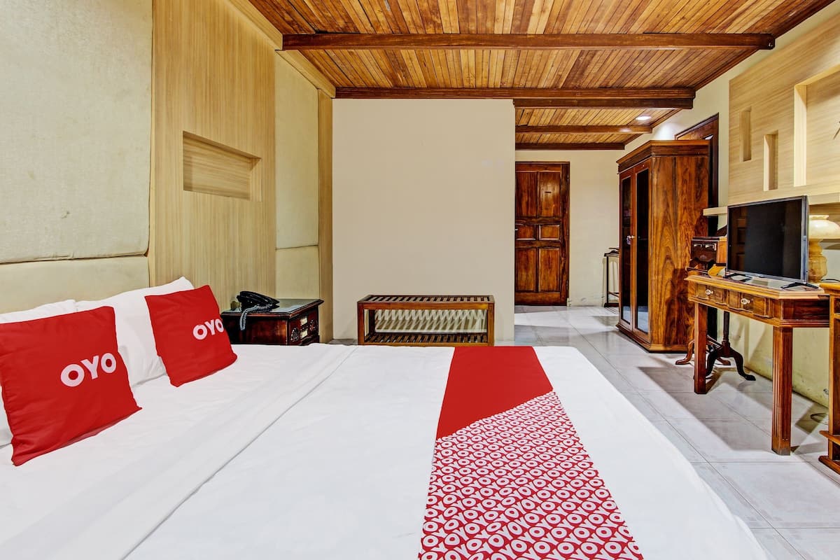 Ein Hotelzimmer mit einem großen Bett, einem Holztisch und einem Fernseher.