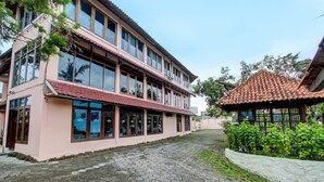 Un bâtiment à deux étages, doté de grandes fenêtres et d’un toit recouvert de tuiles rouges.