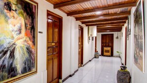 Un couloir avec des portes en bois, un sol carrelé et un tableau accroché au mur.