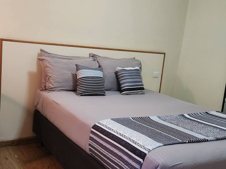 A bedroom with a bed, a desk, and a mirror.