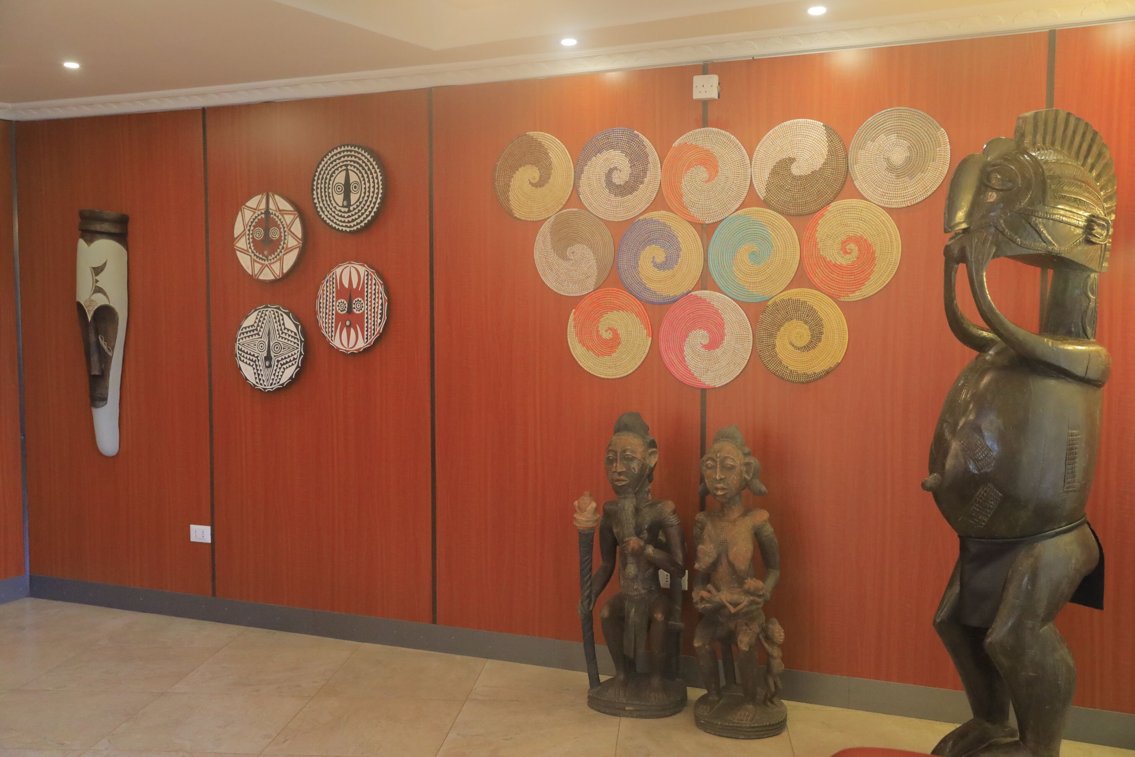 A hallway with wooden paneling, a series of woven baskets on the wall, and a statue of an elephant.