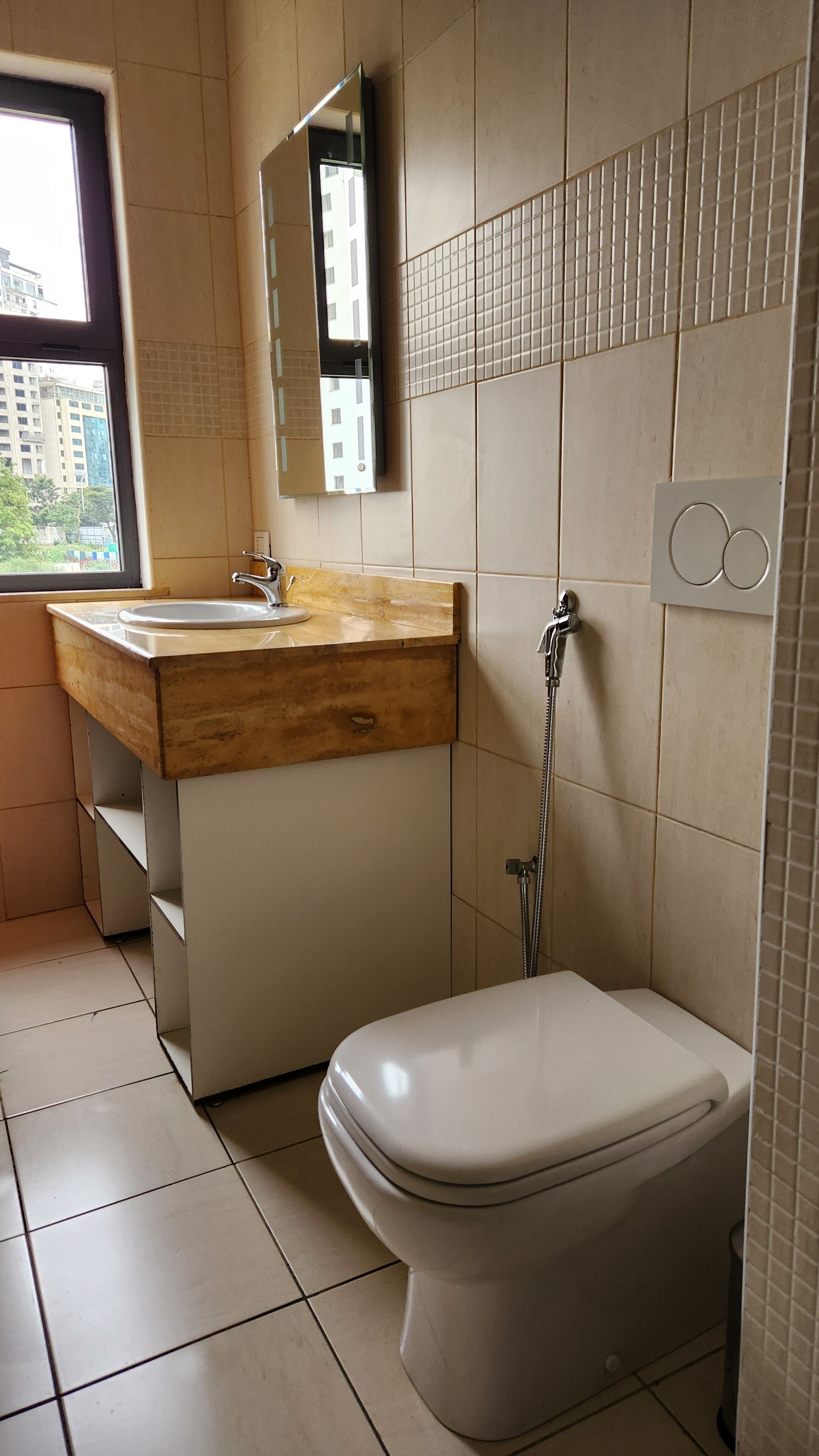 Un baño con inodoro, lavamanos con encimera de madera, espejo y ducha.