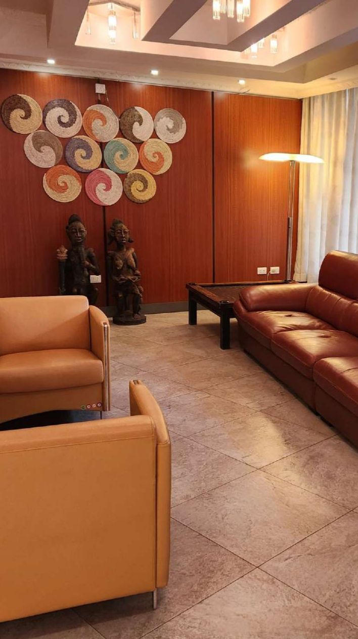A living room with a brown leather sofa, a brown leather armchair, a small coffee table, and a wall with circular wall art.
