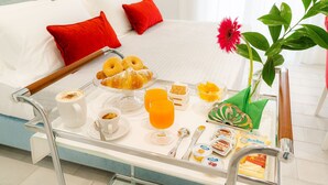 A breakfast trolley with croissants, orange juice, and pastries on a hotel bed. - L'INCANTO DI CIOFFI ROOMS (Sorrento)