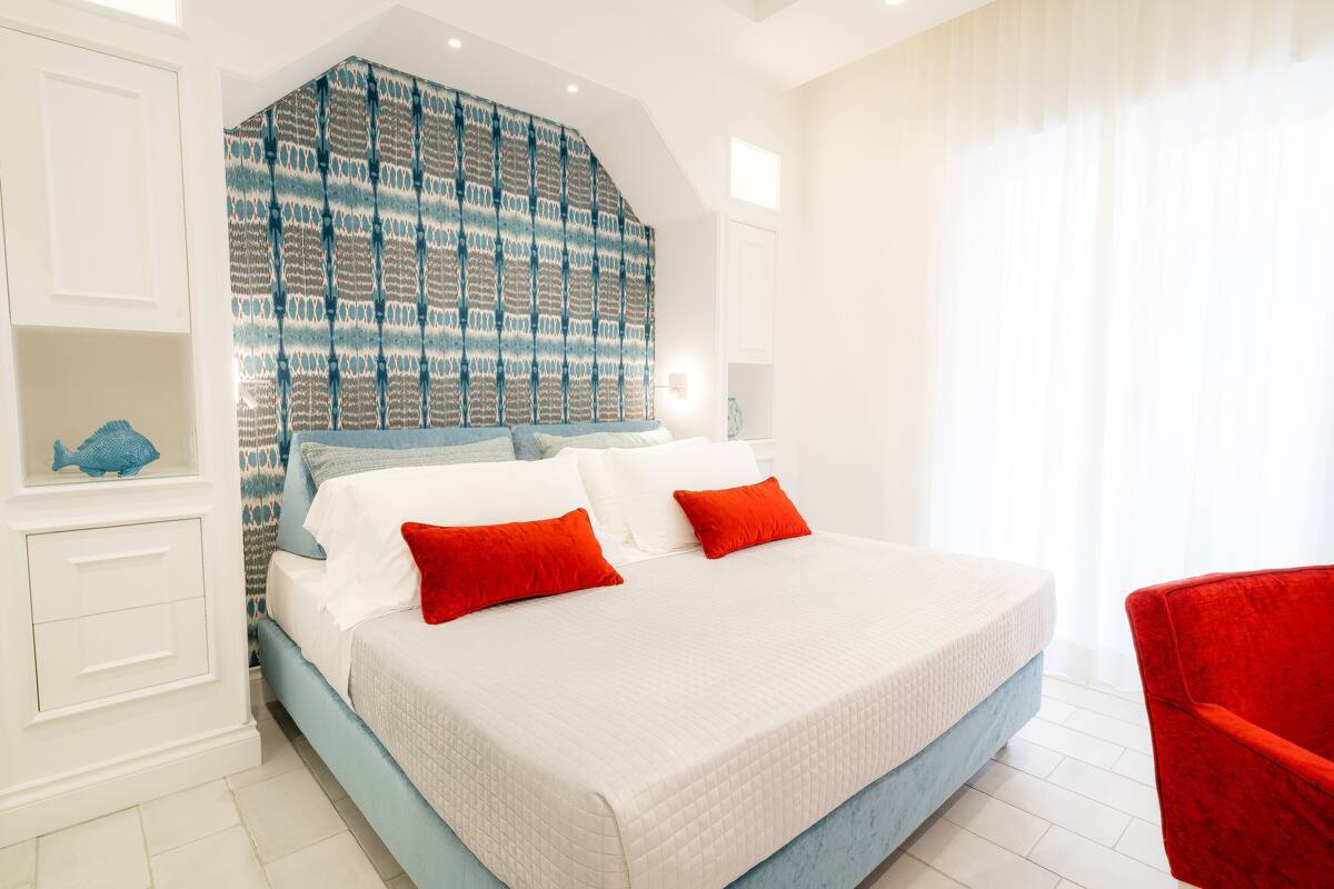 A bedroom with a large bed, white walls, and a patterned headboard.