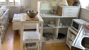 Uma cozinha compacta com armários brancos, bancada de madeira e fogão embutido.